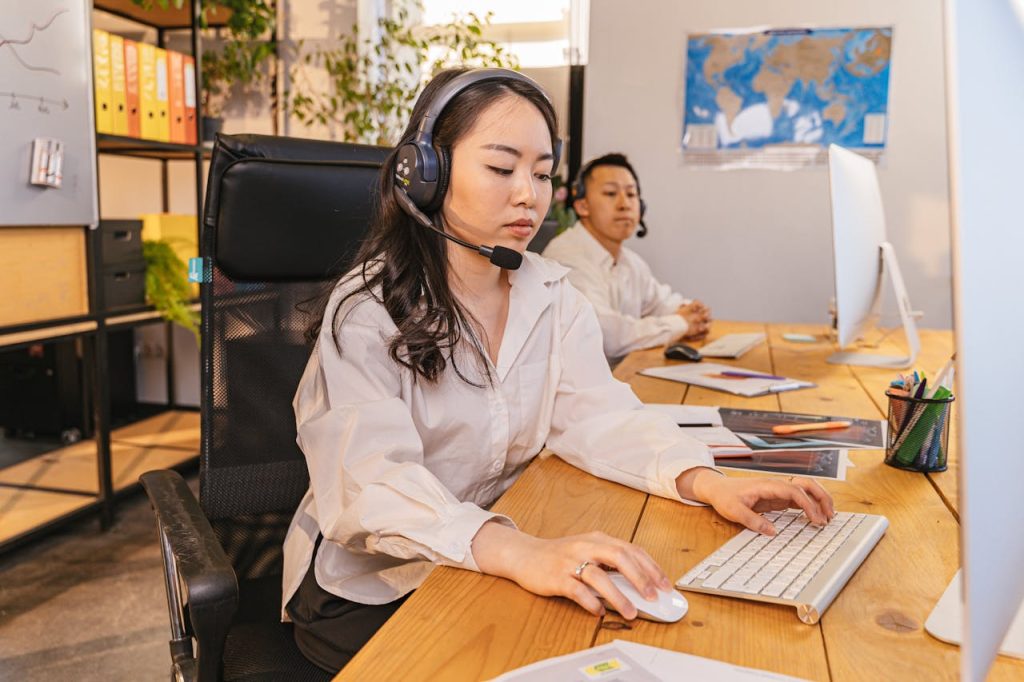 Two call center employees working on computers, focused and efficient, in a modern office setting.
